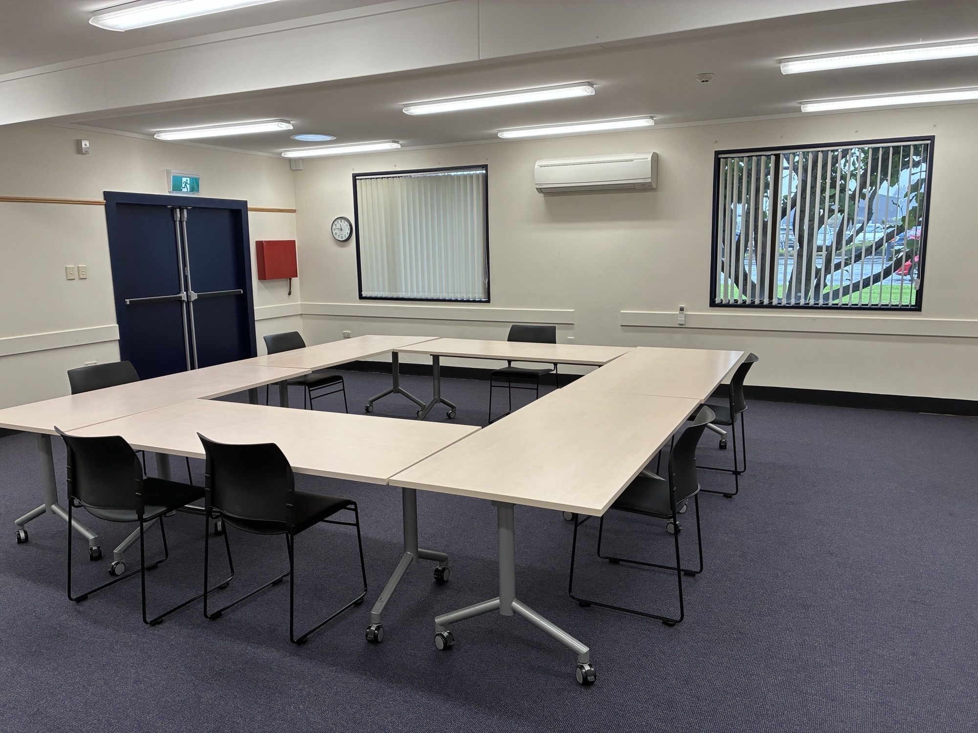 A meeting room with four tables set up in a square shape